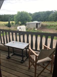 a table and chairs on a porch with a view of a field at Dyrlundgaard tilbyder charmerende ferielejlighed. in Helsinge