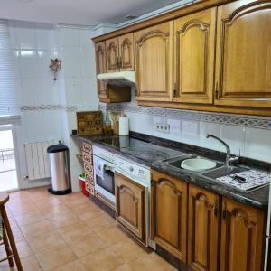 cocina con armarios de madera y horno con fogones en Apartamento El Mirador, en Villaviciosa