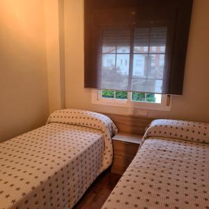 1 dormitorio con 2 camas y ventana en Apartamento El Mirador, en Villaviciosa