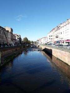 une rivière au milieu d'une ville avec des bâtiments dans l'établissement Le Pinaud, à Épinal