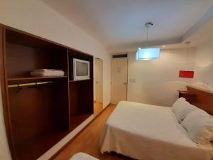 Habitación de hotel con cama y TV en Coronado Hotel en Mina Clavero