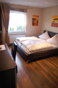 - une chambre avec un grand lit et une fenêtre dans l'établissement Hotel Neuzeit, à Schwalbach
