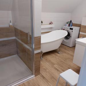 a bathroom with a bath tub and a washing machine at Apartamenty Pod Magnolią in Białowieża