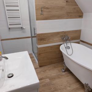 a bathroom with a white tub and a sink at Apartamenty Pod Magnolią in Białowieża