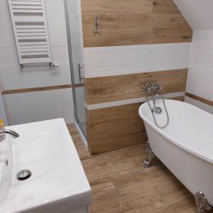a bathroom with a white tub and a sink at Apartamenty Pod Magnolią in Białowieża +89 photos