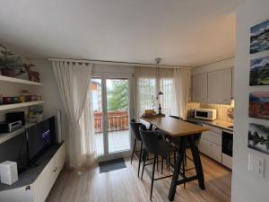 eine Küche mit einem Tisch und Stühlen sowie eine Küche mit einem Balkon in der Unterkunft Ferienwohnung Gemmiblick in Leukerbad