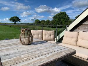 a wooden table with chairs and a basket on a deck at Wood Fired Hot Tub & Pergola with Glass Balcony. in Brecon