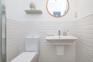 Baño blanco con lavabo y espejo en BHost - NIño Guevara, en Málaga