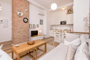 uma sala de estar com um sofá branco e uma parede de tijolos em BHost - NIño Guevara em Málaga