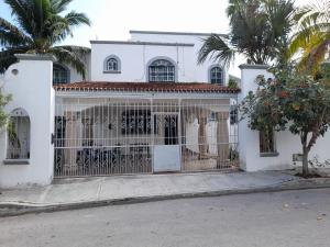 ein weißes Haus mit einem Tor und Palmen in der Unterkunft Claro de Luna in Playa del Carmen