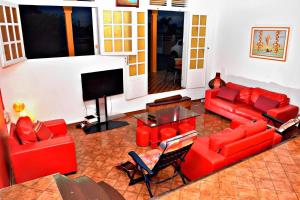 sala de estar con muebles de color rojo y TV de pantalla plana en Villa Punch Alizés 28, Route de la colline 97160 Le Moule en Le Moule