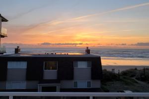 a house on the beach with the sunset in the background at Bela Pacific in Rockaway Beach