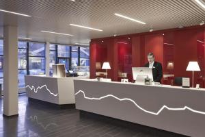 a man standing at a counter in an office with a laptop at Hotel Hans Egede in Nuuk