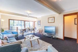 a living room with blue couches and a tv at Baggies On Dutchies, 9 Burbong Street - Large Pet Friendly house with spectacular waterviews, Wi-Fi and air con in Nelson Bay