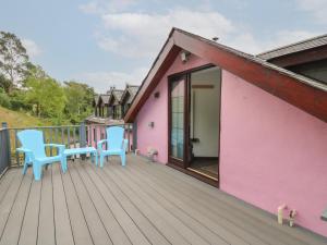 a deck with two blue chairs and a pink house at Tancoed in Aberystwyth