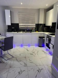 una cocina con encimeras blancas y electrodomésticos con luces púrpuras en 2 Double Bedroom Apartment in Edgware, London, en Edgware