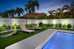 a backyard with a swimming pool and an umbrella at Villa Paradise Miami, Luxury Gem with Heated Pool, Game Room, Fire Pit, 3 Bed 2 Bath in Miami