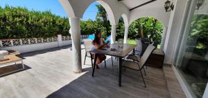 a woman sitting at a table on a patio at Casa Blue Vista - villa & guestroom in Marbella