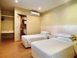 a hotel room with two beds and a bathroom at Fenix Inn in Malacca