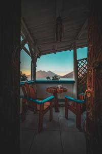 a porch with two chairs and a table with a view at Lush Atitl&aacute;n in San Marcos La Laguna