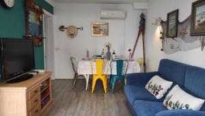 sala de estar con mesa y sofá azul en Casa Marenga El Palo, en Málaga