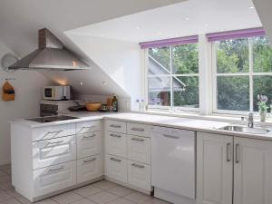una cocina con armarios blancos, fregadero y ventanas en Three-Bedroom Holiday home in Vejby 13, en Vejby