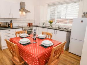 uma cozinha com uma mesa com uma toalha de mesa de bolinhas vermelhas em Hafan Y Mor em Rhôs-on-Sea