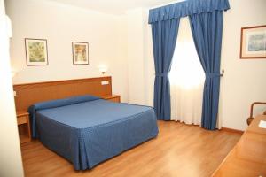 a bedroom with a blue bed and a window at Hotel Peña de Arcos in Arcos de la Frontera