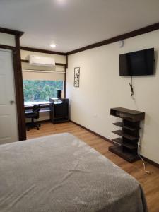 a bedroom with a bed and a desk and a television at Pit Stop Hostel in Aguada