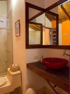baño con lavabo rojo y espejo en La Casa de Pitty, en Máncora