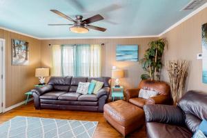 a living room with leather furniture and a ceiling fan at Down By The Sea in Port Aransas