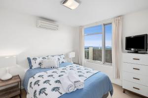 a white bedroom with a bed and a window at Point Grey Apartment 2 in Lorne