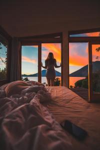 a woman standing in a bed looking out the window at Lush Atitlán in San Marcos La Laguna