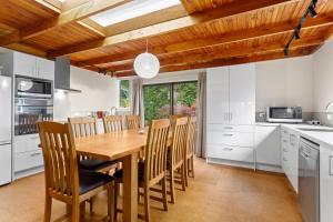a kitchen with a wooden dining table and chairs at Garden House in Opotiki +19 photos