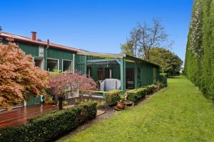 a green house with a garden in front of it at Garden House in Opotiki