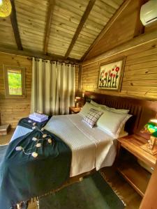 1 dormitorio con 1 cama en una cabaña de madera en Pousada & Camping Nativos dos Canyons en Praia Grande