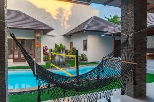 a hammock in front of a house with a swimming pool at 5 BR Villa Sultan Luxury Entertainment and Relaxation in Seminyak