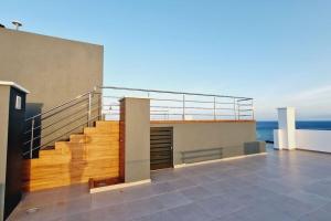 Un balcón de una casa con una escalera de madera en Apartamento encantador com piscina e vista mar, en Praia