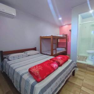 Un dormitorio con una cama con una almohada roja. en Space Hostel , quartos privativos en Arraial do Cabo