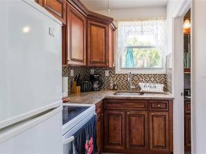 a kitchen with wooden cabinets and a sink and a window at Charming Studio Unit Across from Lido Key Beach in Sarasota