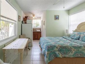 萨拉索塔Charming Studio Unit Across from Lido Key Beach的一间卧室，配有一张床、一张桌子和一台冰箱