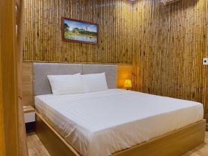 a bedroom with a white bed with a wooden wall at Tam Coc Viet Ha Homestay in Ninh Binh