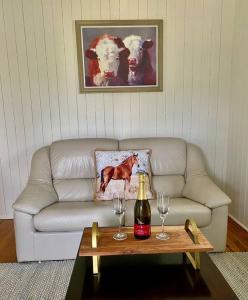 un soggiorno con un divano e un tavolo con bicchieri da vino di The Cottage Country Escape a Coolabine