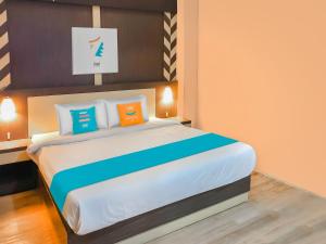 パランカラヤにあるSans Hotel City Inn Palangkarayaのベッドルーム1室(大型ベッド1台、オレンジ&ブルーの枕付)