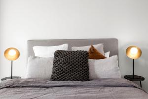 a bedroom with a bed with pillows and two lamps at Luxuria Apartments - Fulton Lane in Melbourne