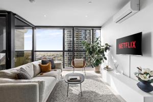 a living room with a couch and a tv at Luxuria Apartments - Fulton Lane in Melbourne