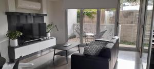 een woonkamer met een bank en een flatscreen-tv bij Impressive Central Apartment in Warrnambool