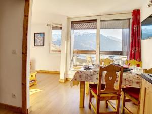 ein Esszimmer mit einem Tisch und einem großen Fenster in der Unterkunft Appartement cosy aux Menuires · Accès pistes · Parking inclus - FR-1-344-850 in Les Menuires