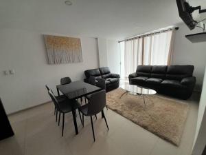 uma sala de estar com um sofá preto e uma mesa e cadeiras em Elegante departamento en Urbarí - Cond. Aruma em Santa Cruz de la Sierra
