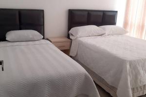 two beds sitting next to each other in a bedroom at Elegante departamento en Urbarí - Cond. Aruma in Santa Cruz de la Sierra +2 photos
